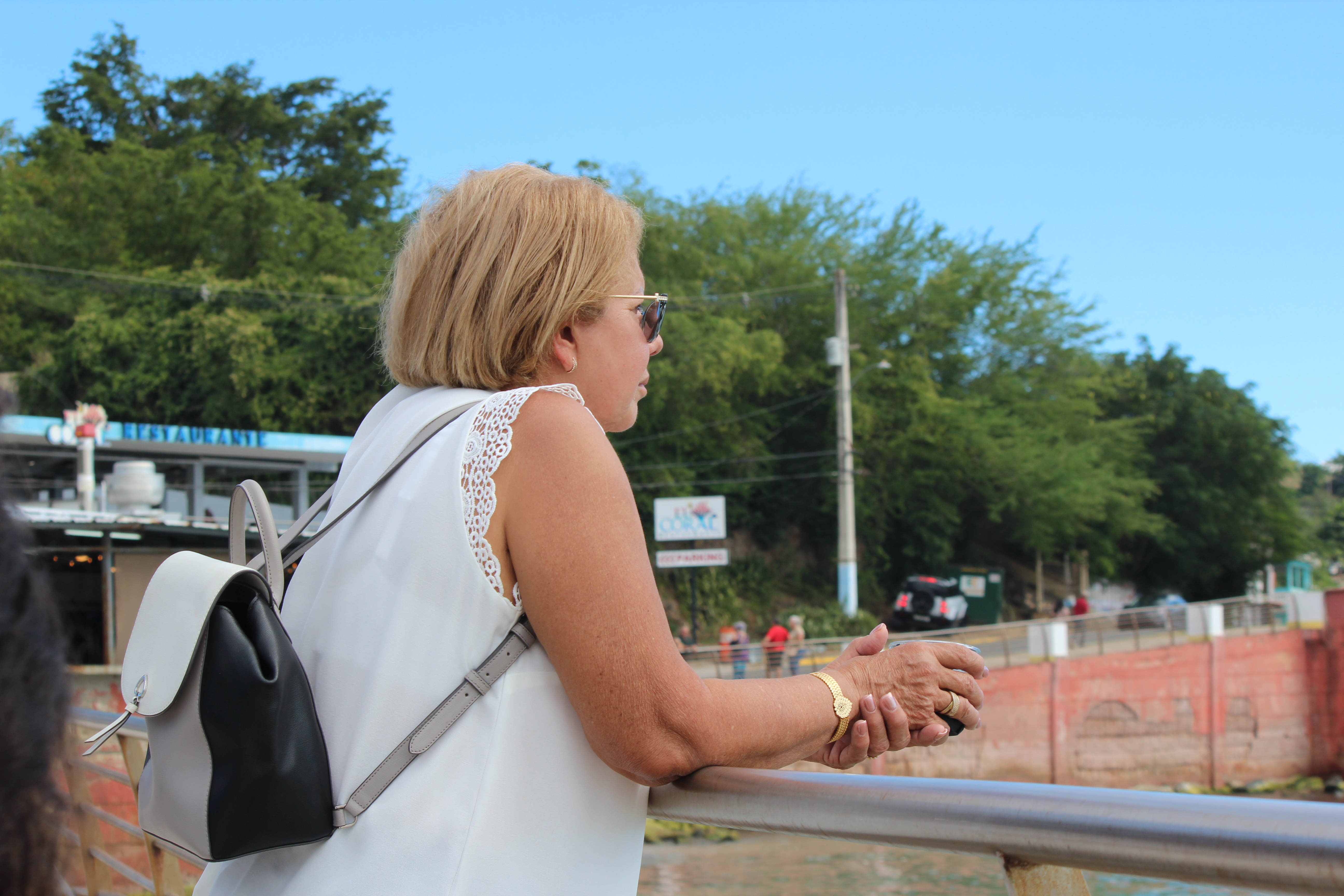 Woman leaning on fence looking into the ocean